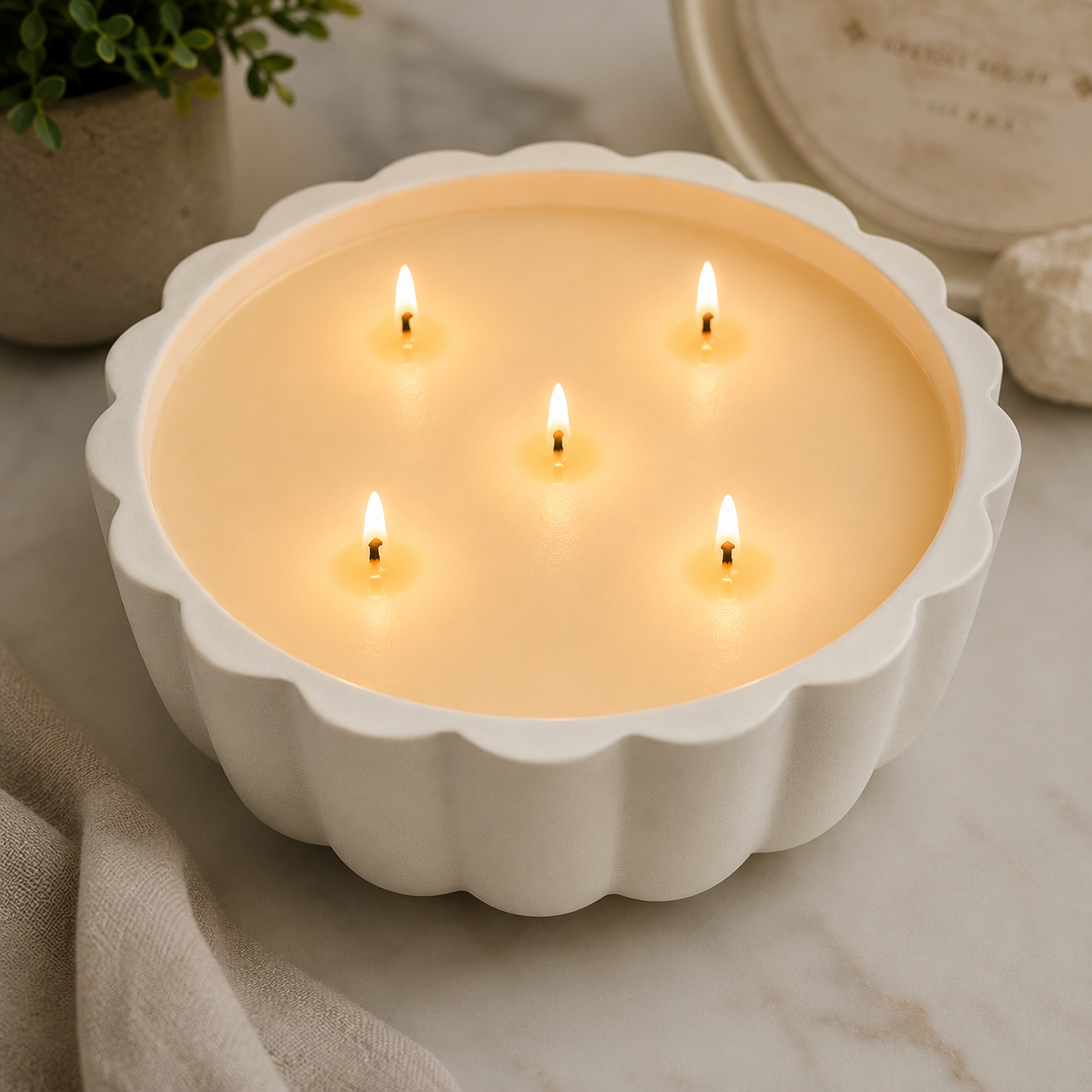White ceramic bowl with five lit candles on a marble surface.