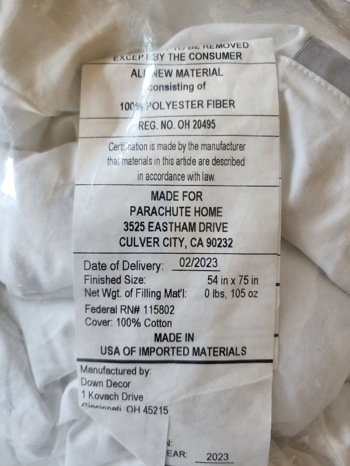 Label on a mattress topper with product details and manufacturing information.