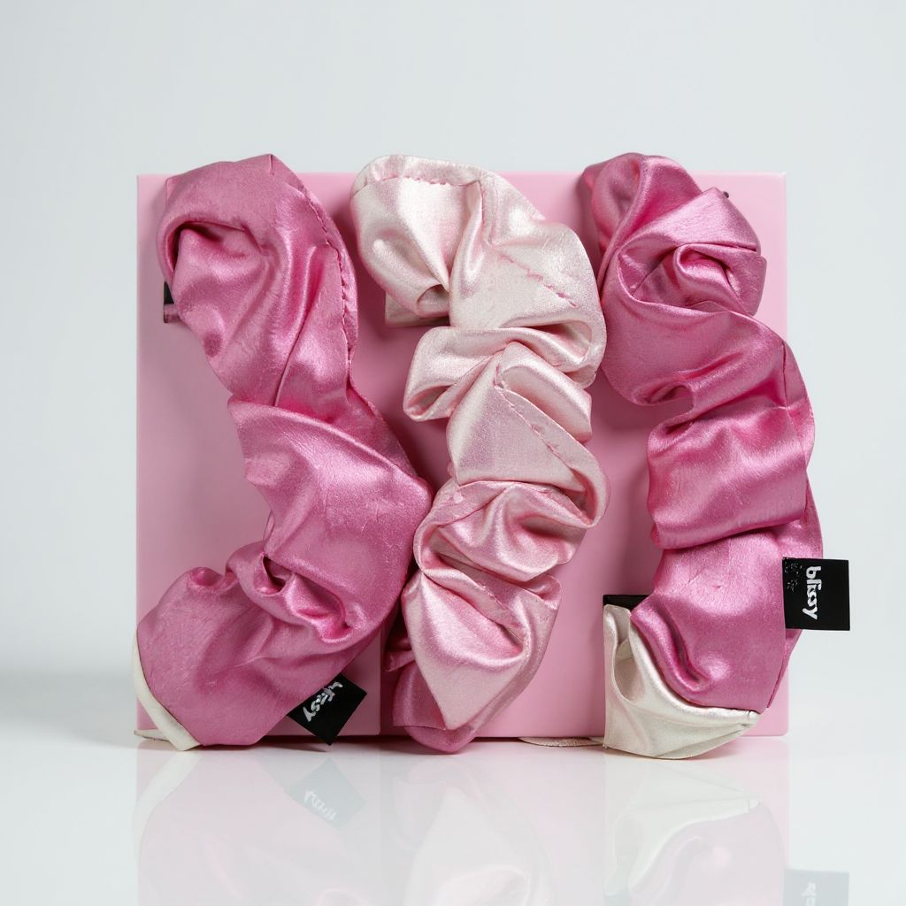Pink and white satin scrunchies in a box on a light gray background