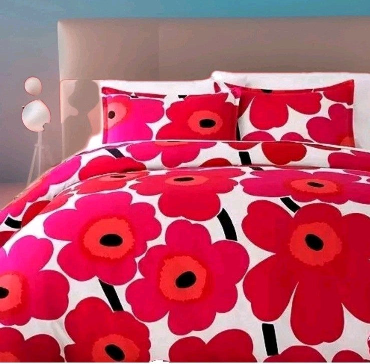 Floral bedding set with red and pink flowers on a bed in a bedroom setting.